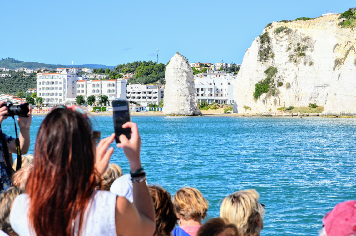 turisti durante escursione in barca fotografano Pizzomunno a Vieste nel Gargano